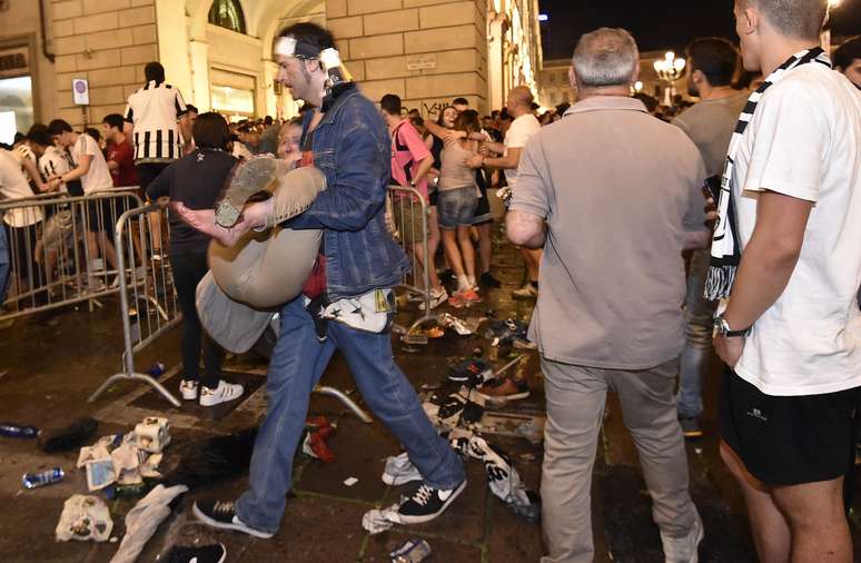 Homem carrega pessoa ferida em confusão em praça de Turim