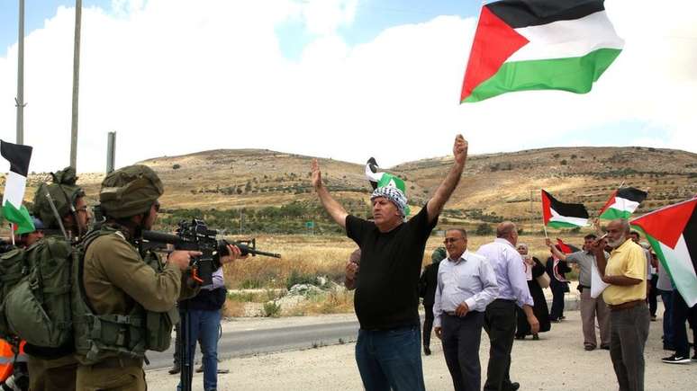 Manifestante palestino da Cisjordania protesta em frente a soldados israelenses