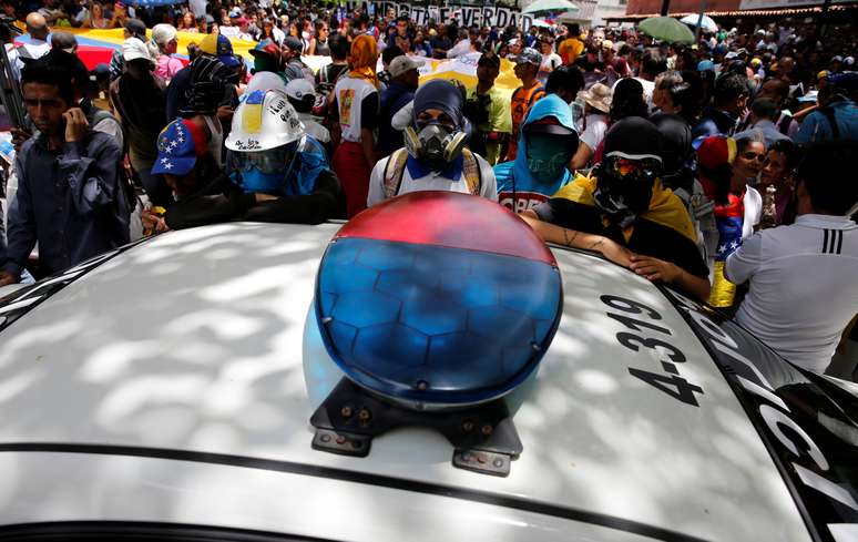 Manifestantes cercam veículo de patrulha durante o protesto contra o governo de Maduro em Caracas