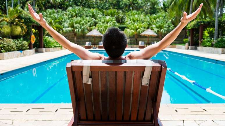 Homem sentado em volta de piscina