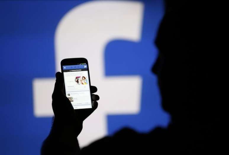 Homem acessa Facebook em celular diante de proje&ccedil;&atilde;o do logo da rede social
14/08/2013 REUTERS/Dado Ruvic/File Photo
