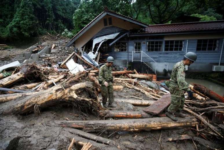Soldados japoneses caminham em meio a destroços deixados pelas chuvas em Toho. 07/07/2017 REUTERS/Issei Kato