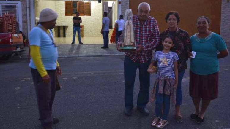 Brasilina de Medeiros Gonçalves (de óculos) leva a neta de 7 anos para ver a santa quase diariamente 