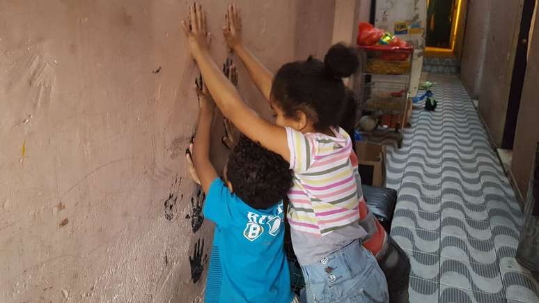 Filhos de Renata brincam no corredor de cortiço onde moram no centro de SP