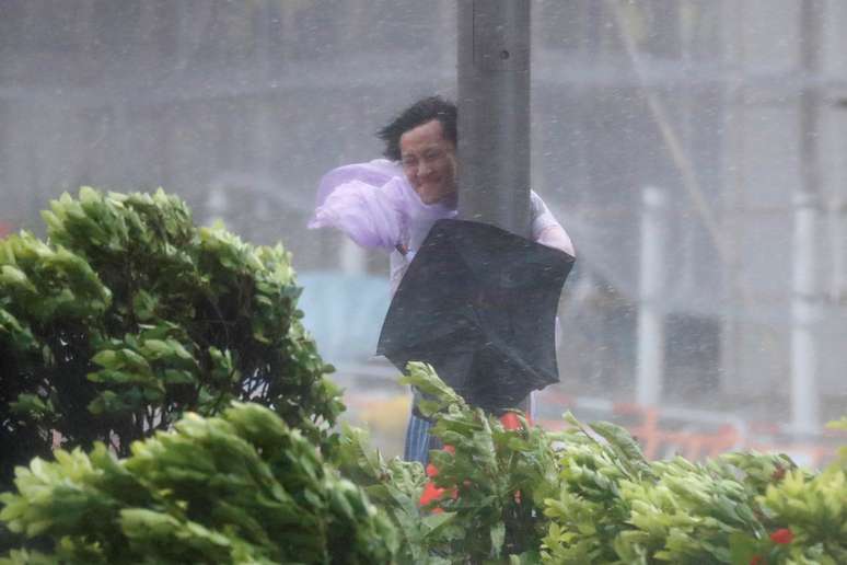 Homem se segura em poste durante fortes ventos causados pelo tufão em Hong Kong