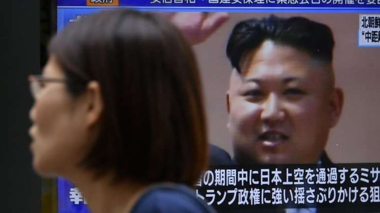 Pedestre em Tóquio passa diante de tela com imagem de Kim Jong-un