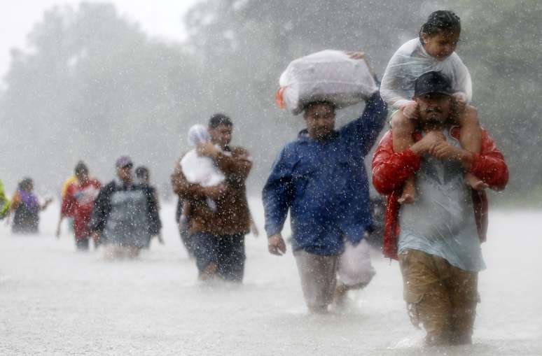 Moradores atravessam via alagada pela tempestade tropical Harvey em Beaumont, no Texas