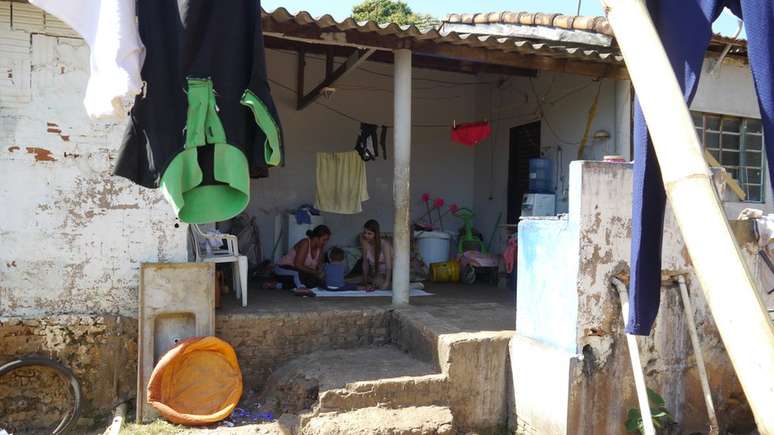 M&atilde;e, crian&ccedil;a e visitadora do Crian&ccedil;a Feliz, sentadas no ch&atilde;o na varanda da casa (foto: Amanda Rossi/BBC Brasil)