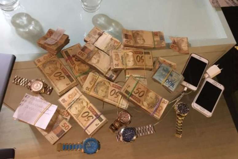 Dinheiro, celulares e relógios apreendidos pela Polícia Federal durante a Operação Brabo, deflagrada para desarticular um esquema internacional de tráfico de drogas  