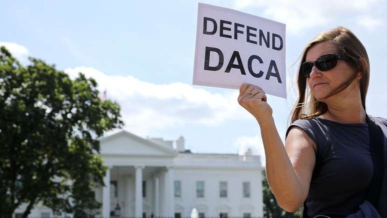 Mulher com cartaz com os dizeres Defenda DACA