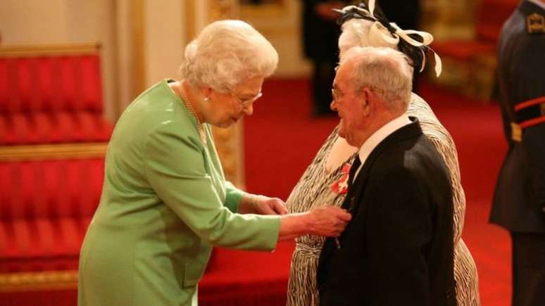 Casal de idosos em traje de gala recebe condecoração da rainha da Inglaterra
