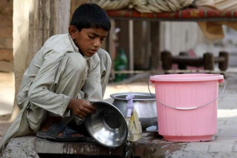 Menino trabalha em loja de alimentação em Peshawar, no Paquistão