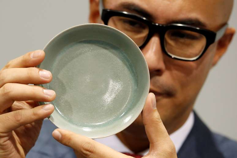 Nicholas Chow, Deputy Chairman for Sotheby's Asia and the International Head and Chairman of the Chinese Works of Art department, poses with a rare Ru Guanyao brush washer, after it sold for $37.7 million during an auction in Hong Kong, China October 3, 2017. REUTERS/Bobby Yip 
