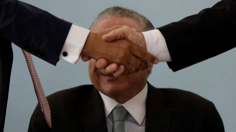 Aperto de m&atilde;o cobre o rosto do presidente Michel Temer