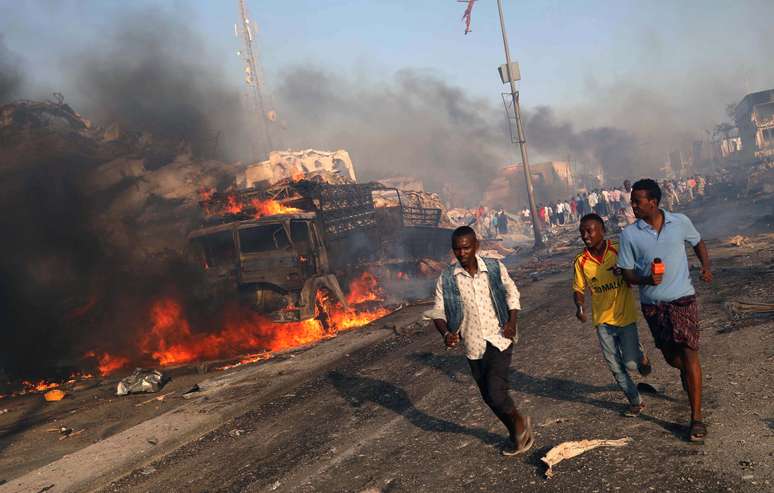 Homens deixam local da explosão na Somália