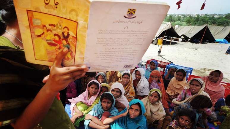 Garotas paquistanesas ouvem a professora em uma escola improvisada