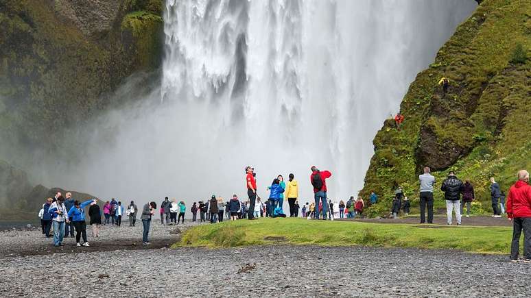 Turistas próximos a uma cachoeira na Islândia