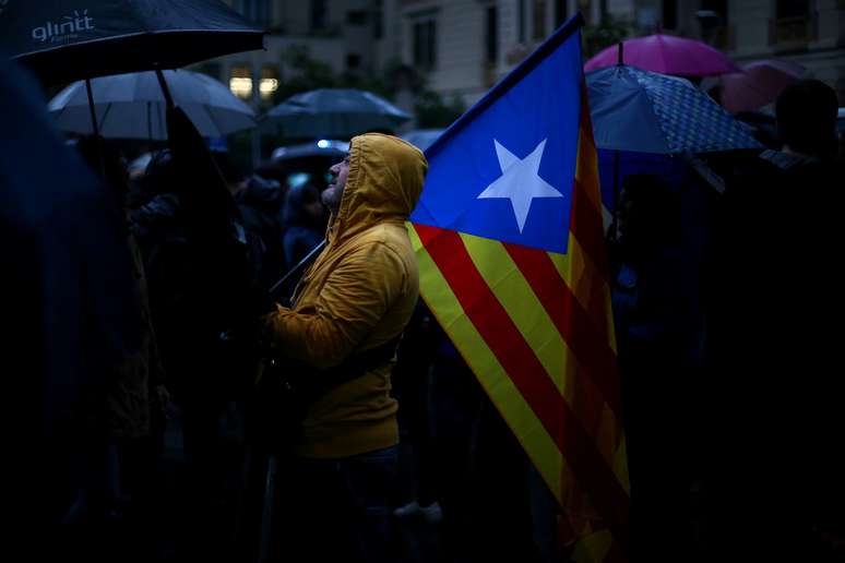 Manifestante segura bandeira separatista da Catalunha durante protesto em Barcelona, Espanha