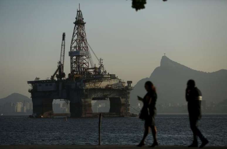 Pessoas passam por plataforma de petr&oacute;leo em Niter&oacute;i, no Rio de Janeiro 20/04/2015 REUTERS/Pilar Olivares