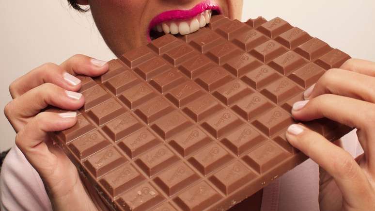 Mulher devorando uma barra de chocolate.
