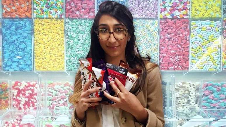 Radhika Sanghan em uma montagem segurando muitos doces