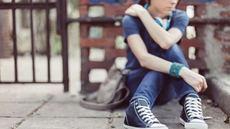 Adolescente sentada no ch&atilde;o