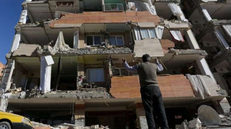 Morador em frente a prédio destruído na província iraniana de Kermanshah
