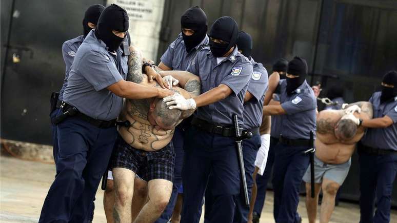 Integrantes da gangue MS-13 são levados para área de isolamento em prisão de El Salvador; segundo o FBI, o lema da organização é 'matar, estuprar, controlar'