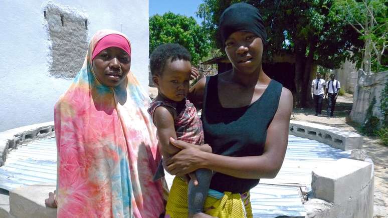 Anchia Enusso e a amiga Mimi Assane compram baldes de água na casa da vizinha, uma das poucas com abastecimento encanado no bairro | Foto: Amanda Rossi/BBC Brasil