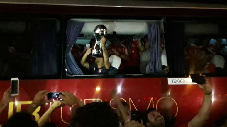 Jogadores do Independiente comemoram com a taça da Sul-Americana na janela do ônibus que foi quebrada (Foto: Igor Siqueira)