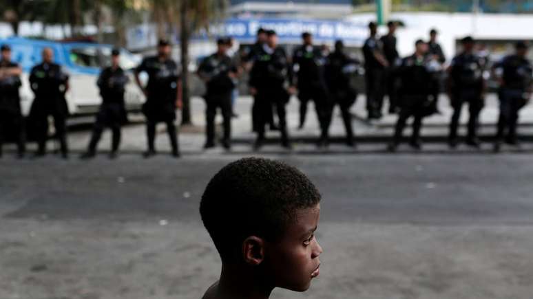 Na Rocinha, menino observa movimentação de policiais; a explosão da violência no Rio se expressa também na vulnerabilidade das crianças a ela