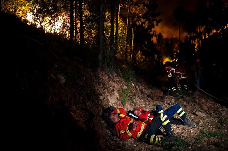 Bombeiros descansam durante inc&ecirc;ndio em Penela, regi&atilde;o central de Portugal. Uma onda de inc&ecirc;ndios florestais matou mais de 30 pessoas e deixou dezenas de feridos no ver&atilde;o europeu. Mais de 3,8 mil bombeiros e socorristas foram mobilizados na tentativa de conter as chamas