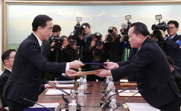 Líder da delegação norte-coreana, Ri Son Gwon, troca documentos com colega sul-coreano, Cho Myoung-gyon, após reunião bilateral no vilarejo de Panmunjom 09/01/2018 Yonhap via REUTERS
