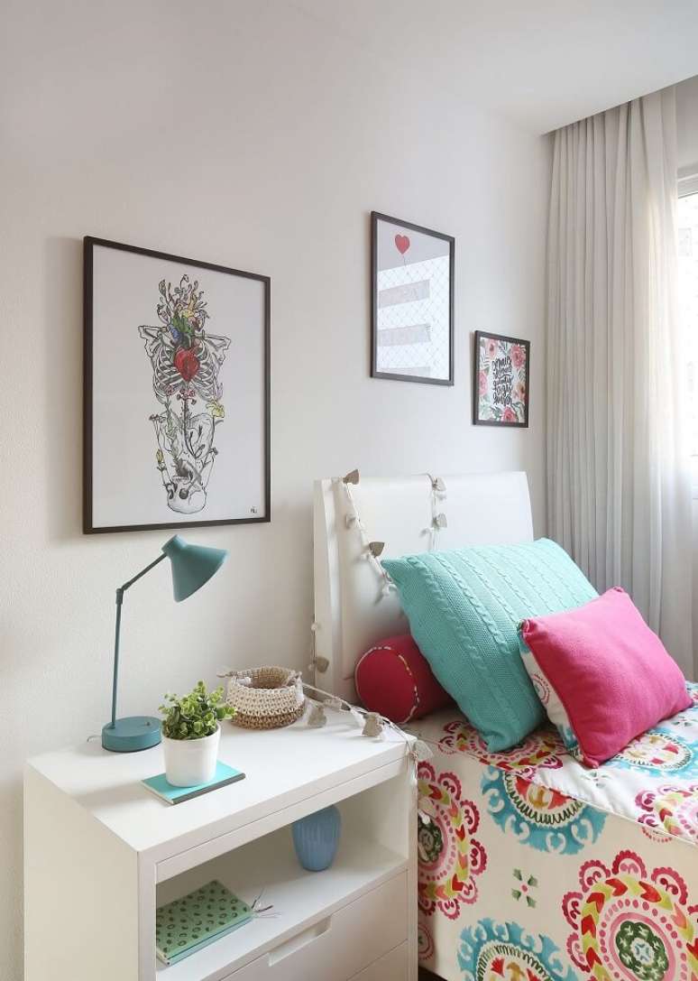 42.Decoração de quarto de solteiro com criado mudo branco, almofadas coloridas e luminária azul