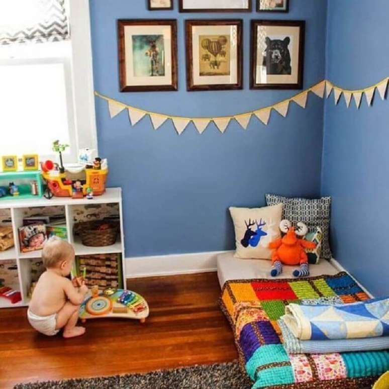 27. Modelo de quarto de menino com paredes azuis, bandeirinhas na parede e piso de madeira