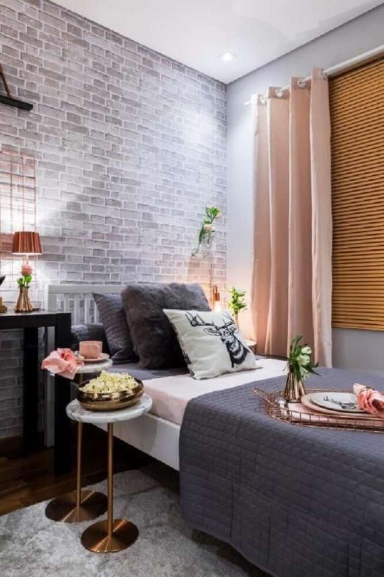 6. Quarto decorado em tons de cinza, rosa e cobre e papel de parede de tijolinhos.