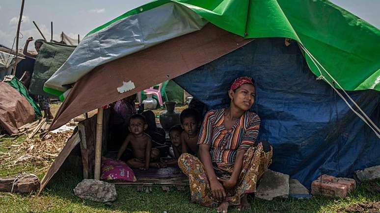 Mulher rohingya senta ao lado dos filhos em abrigo temporário