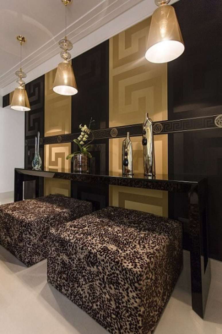 25. Este papel de parede para sala Versace em preto e dourado deixa o ambiente mais sofisticado. Projeto de Helen Granzote