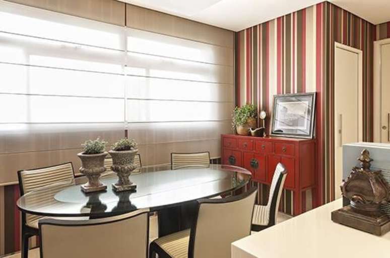 38. Visão mais ampla da sala de jantar com papel de parede para sala listrado seguindo a paleta do ambiente. Projeto de Glaucia Britto