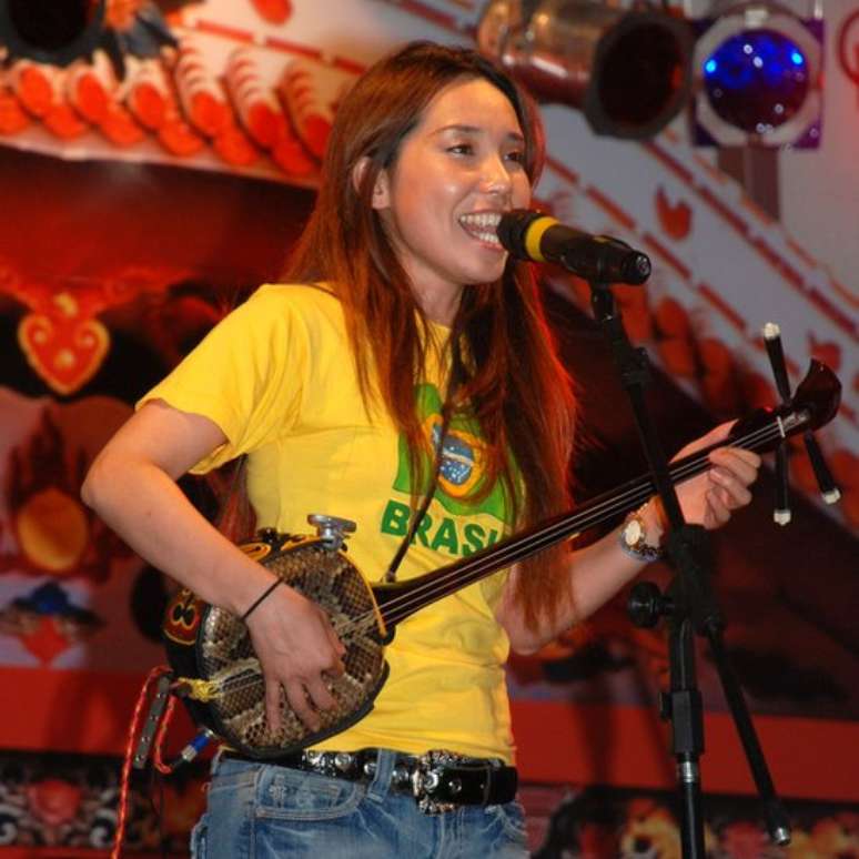 A cantora Megumi Guchi toca o sanshin, instrumento tradicional de Okinawa | Foto: Associa&ccedil;&atilde;o Okinawana Kenjin do Brasil