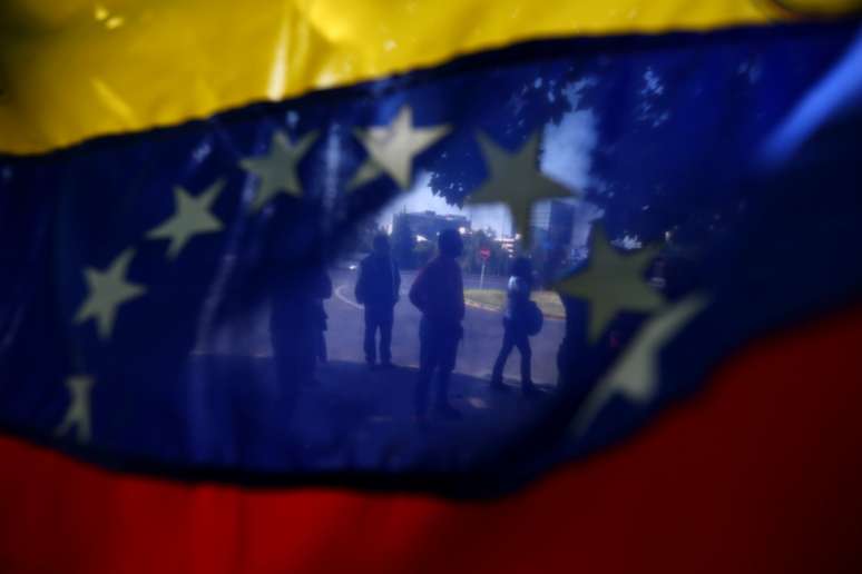 Manifestantes são vistos através da bandeira da Venezuela durante protesto contra o governo em Santiago 23/01/2018 REUTERS/Ivan Alvarado
