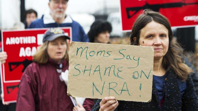 Mulher segura cartaz em que lê-se 'Mães dizem: que vergonha, NRA', em protesto contra a NRA