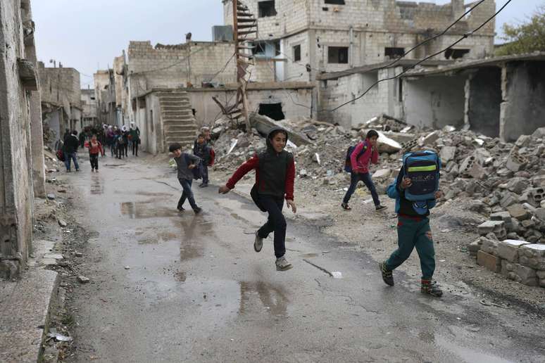 Estudantes passam perto de prédios destruídos na cidade síria de Deraa
 25/1/2018    REUTERS/Alaa al-Faqir
