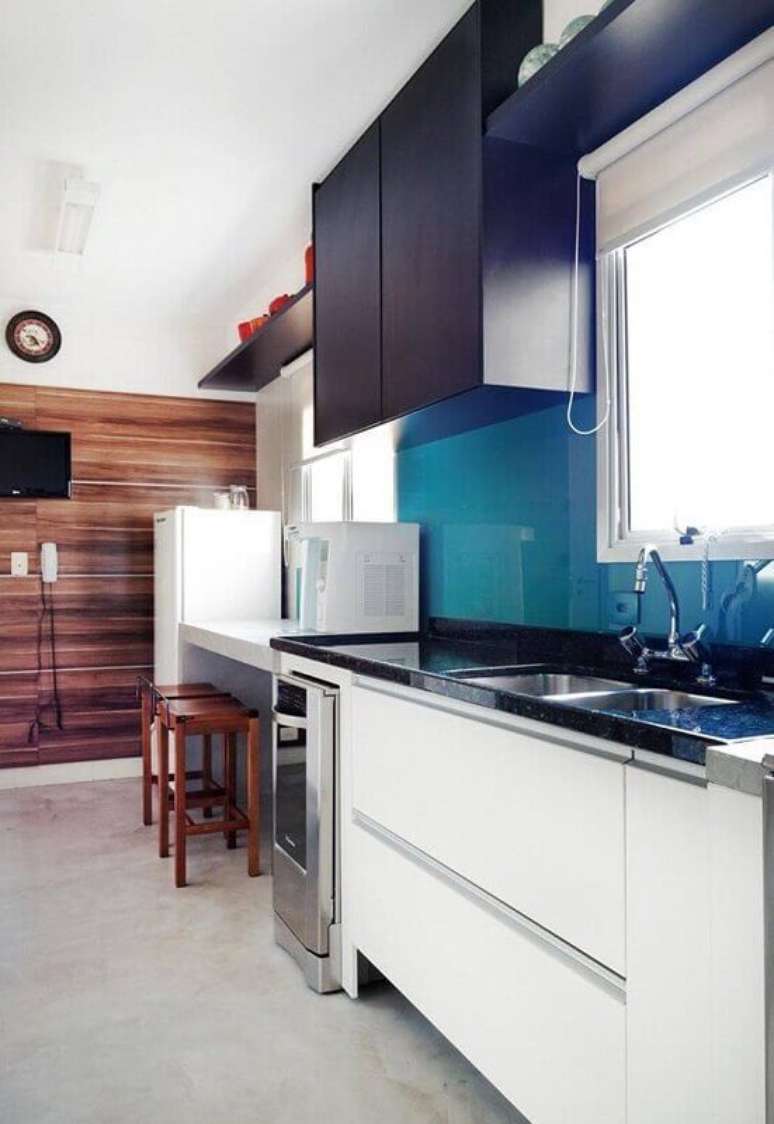 32. Móveis em azul, preto, branco e uma parede de madeira fizeram a cozinha planejada ficar ainda mais bonita