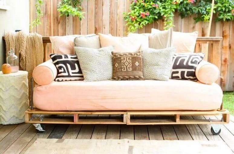 6. Lindo sofá de pallet em tom de rosa e com muitas almofadas compondo a decoração.