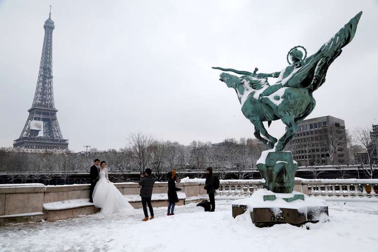 Noivos fazem fotos de casamento em frente à torre Eiffel em meio à neve