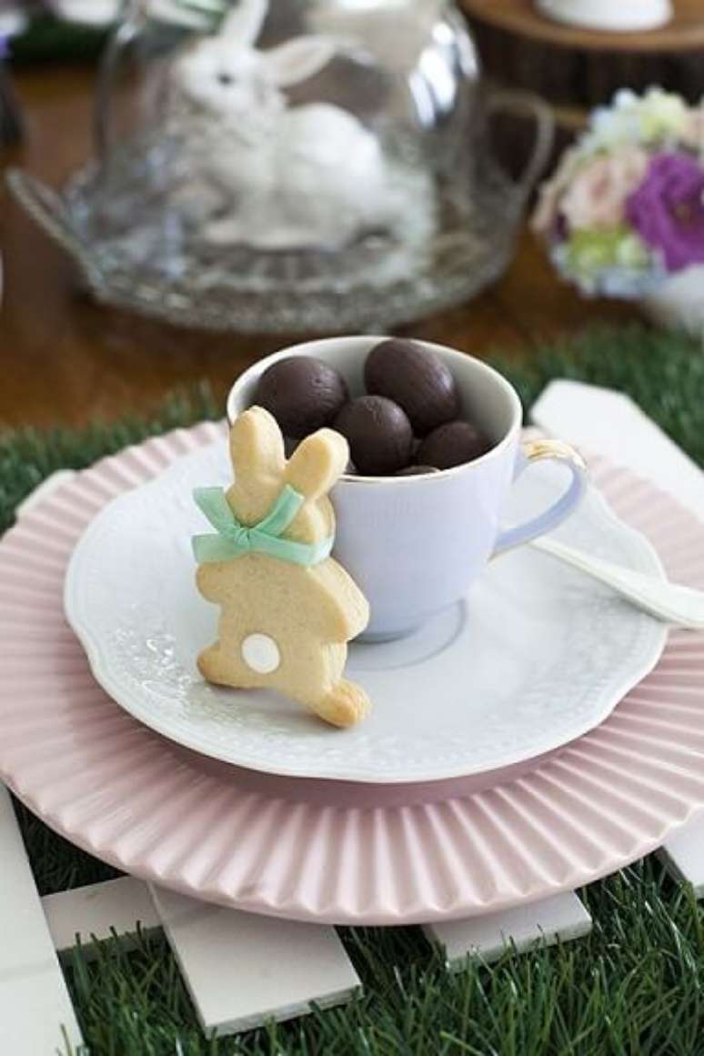 34. Decoração de páscoa com mini ovos em xícara e biscoito de coelho
