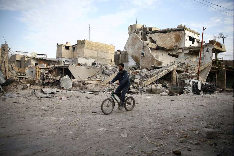 Homem em bicicleta perto de casas destruídas em Ghouta Oriental 
 20/2/2018    REUTERS/Bassam Khabieh