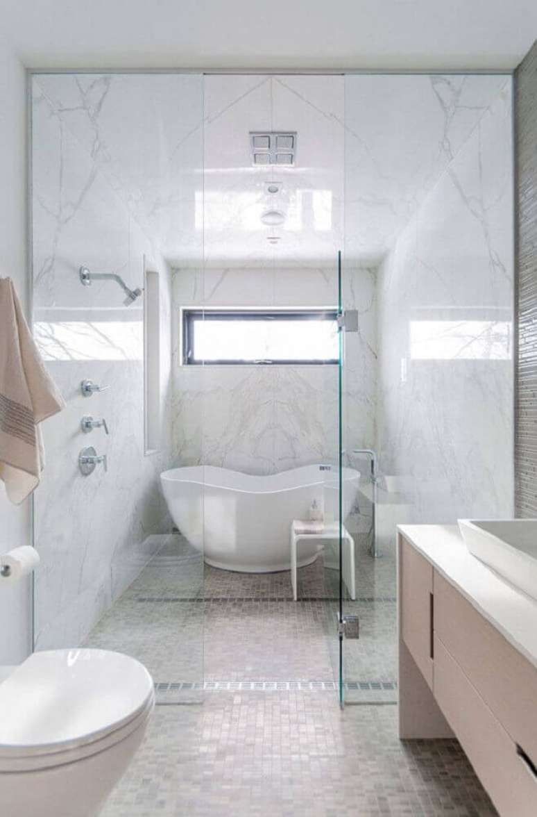 44. Decoração de banheiro em tons claros com banheira e box de vidro