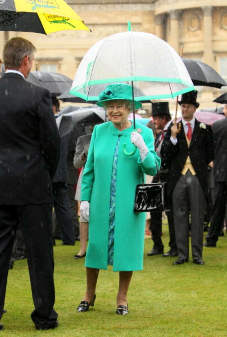 A rainha tem coleções de guardas-chuva transparentes com tecidos que combinam com suas roupas. A imagem é de 19 de julho de 2011 e foi feita nos jardins do Palácio de Buckingham